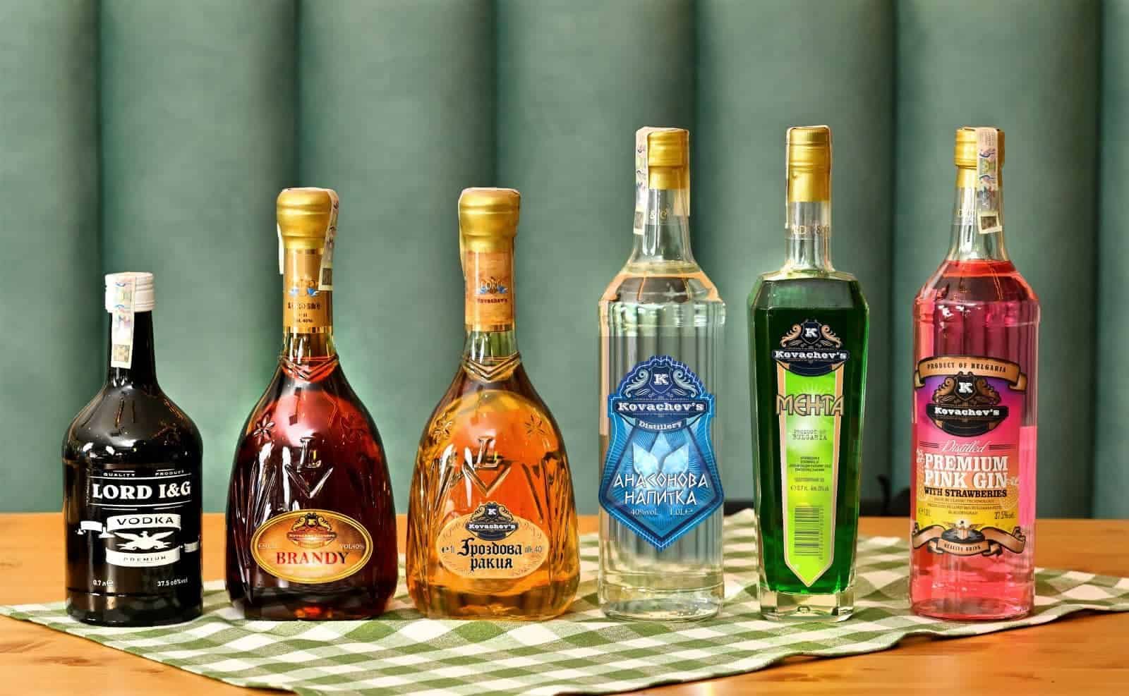Bottles of assorted liquors and spirits displayed on a wooden table with a green checkered cloth.