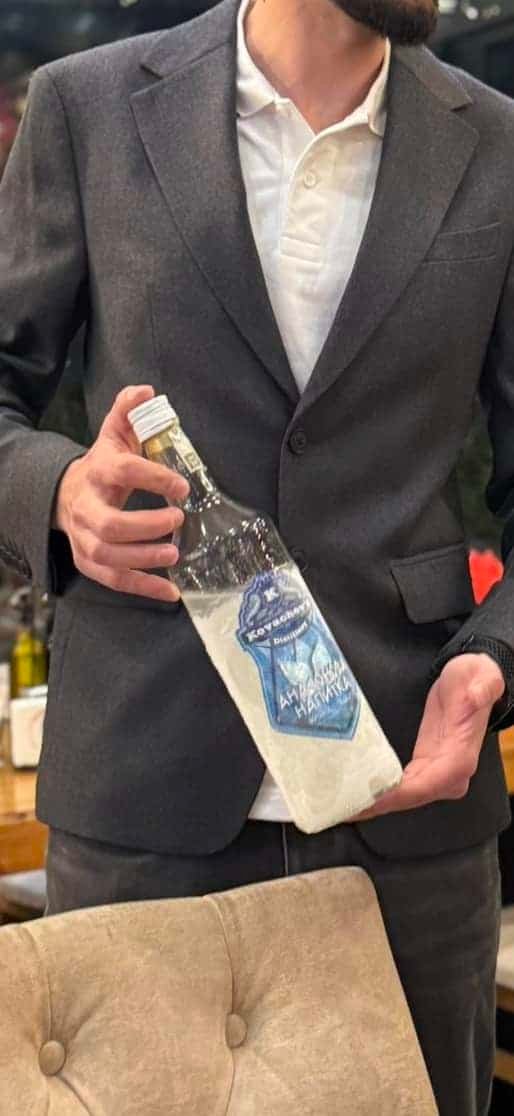 Handsome man holding a custom liquor bottle with cloth in a stylish setting.
